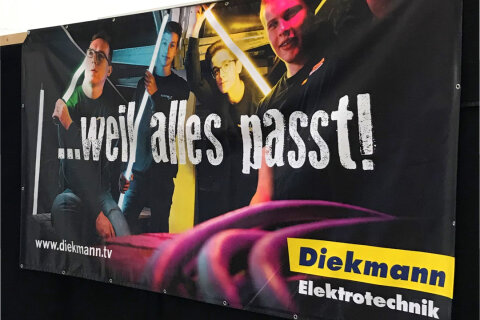 Ein Banner der Firma Diekmann mit Azubis und Neonlampen, mit Aufschrift: weil alles passt!